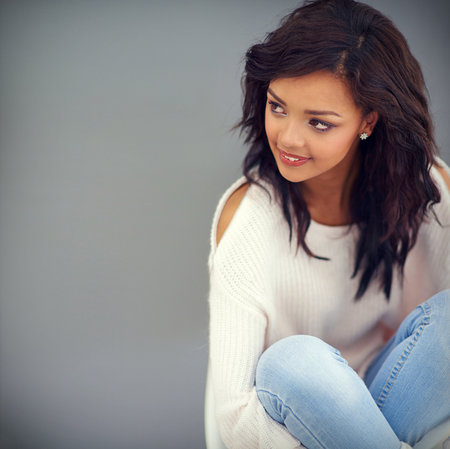 She likes her style comfortable and casual. Studio shot of an attractive young woman posing against a gray background.の写真素材