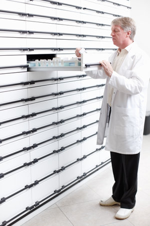 Pharmacist looking for medicines. Full length of handsome pharmacist searching for medicine in pharmacy.の写真素材