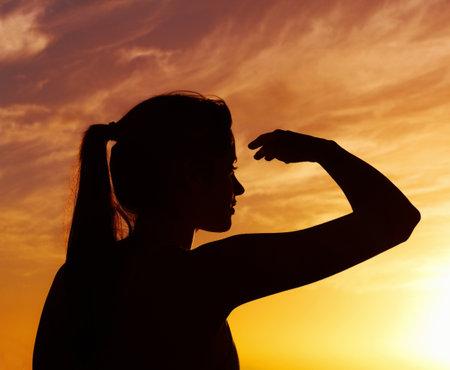 Silhouetted woman looking at something interesting at sunset. Silhouette of a woman looking at something interesting against beautiful sky at sunset.の写真素材