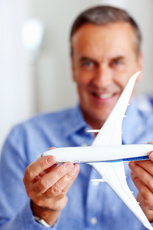 Happy senior man holding toy plane in front of you. Closeup portrait of a happy senior man holding toy plane in front of you.の写真素材