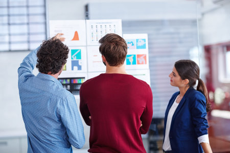 Playing around with different designs. Rearview shot of creative professionals working together on designs.の写真素材