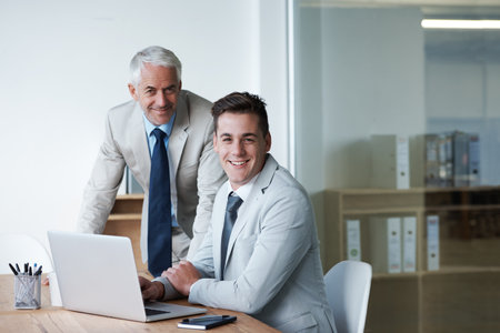 They are confident in their business decisions. Portrait of two corporate businessmen with a laptop in front of them.の写真素材
