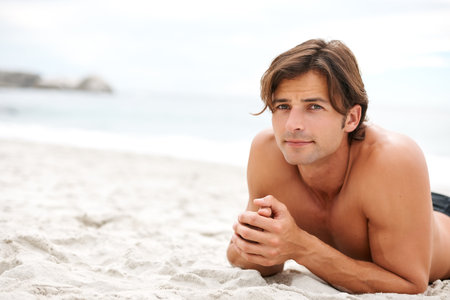 All I need is beach. a handsome young man enjoying a relaxing day at the beach.の写真素材