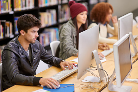 He takes his studies seriously. students working on computers in a university library.の写真素材