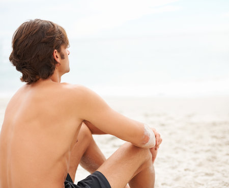 The waves of the sea help me get back to me. a handsome young man enjoying a relaxing day at the beach.の写真素材