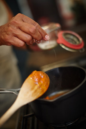 Seasoned with salt. Closeup shot of a woman adding salt to the pot on the stove.の写真素材