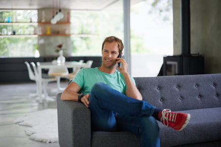 Wanna make plans. A young man chatting on his cellphone at home.の写真素材