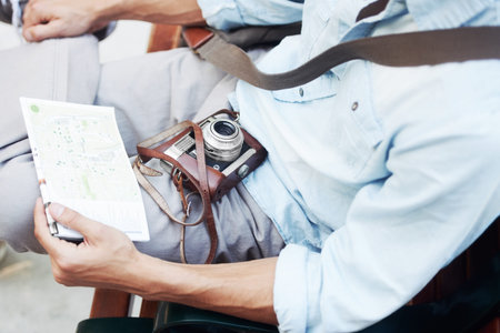 Drawing inspiration from relaxation. Closeup cropped image of a young male resting a map and camera on his lap.の写真素材