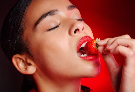 Face, eating and woman with red strawberry for fruit detox, health wellness goals or nutritionist diet. Lipstick makeup, erotic. beauty and sexy model girl with food product, skincare and cosmeticsの写真素材