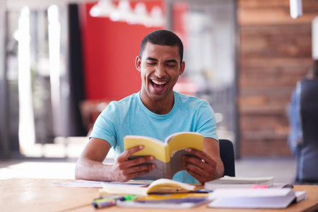 Who said education cant be fun. a college student laughing while reading a book.