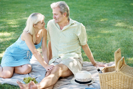 Making the time to keep romance alive. A smiling husband and wife enjoying a leisurely picnic in the park.の写真素材
