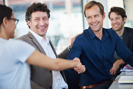 You deserve your success. two business people shaking hands while sitting at a table.の写真素材