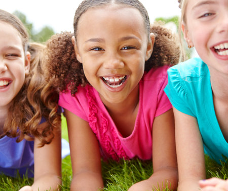 She always has fun with her best friends. Three multi-ethnic young girls lying on the grass in a...