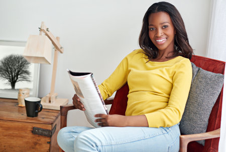 You can have it after me...a young woman relaxing at home with a magazine.の写真素材