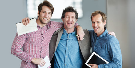 Colleagues and buddies. Portrait of a group of laughing coworkers standing arm in arm together in an...