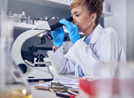 Science, laboratory and black woman with microscope, research for vaccine development. Healthcare, medical innovation and senior scientist woman in hospital lab looking at pharmaceutical test resultsの写真素材