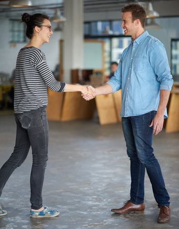 Welcoming the newbie. Male and female creative proffesionals greeting each other with a handshake.