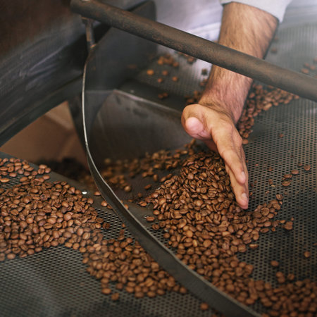 Hand-sifted beans. a mans hand sifting coffee beans in a grinder.
