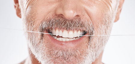 Dental, floss and mouth of senior man in studio isolated on a gray background. Hygiene, cleaning and...