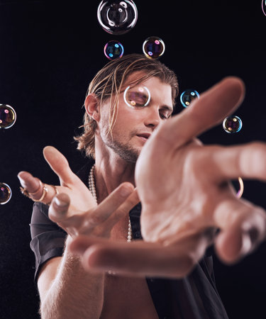 Man, hands and bubbles in studio for magic, art performance or creative show by black background....
