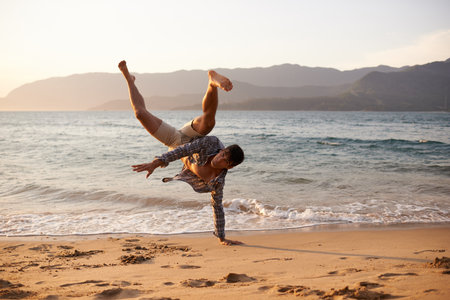 Getting his breakdance on. a young man dancing on the beach.の写真素材