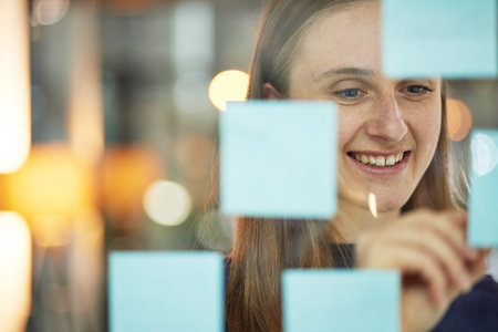 Planning, strategy and woman writing on glass wall sticky note, brainstorming idea for creative...