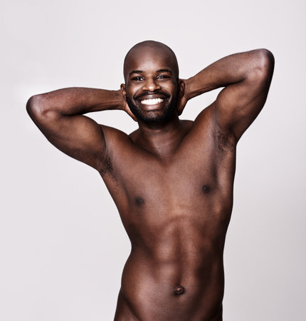 Showing off his muscular perfection. Studio shot of a muscular man with his arms behind his head isolated on white.の写真素材