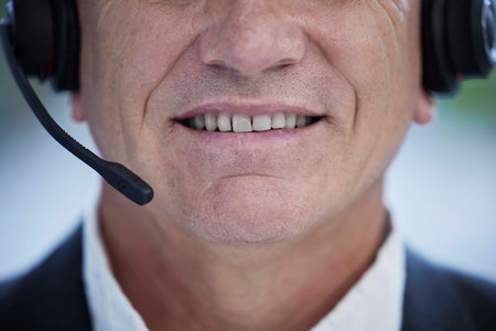 Closeup, call center and man with headphones, customer support and help in office. Agent, senior male and consultant with headset, communication and crm expert for support, salesman and telemarketingの写真素材