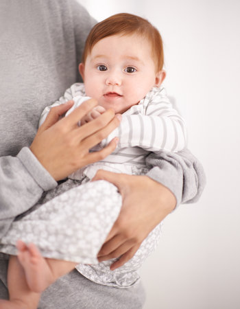 Mommy says only one more month before I start crawling. Portrait of a baby in her mothers arms.の写真素材