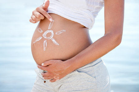 Belly bonding. a pregnant woman with the sun drawn onto her belly against the background of the...