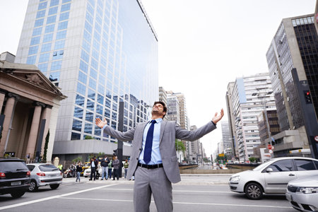 I love the city. A contented young businessman standing in the city with his eyes closed and his arms raised.の写真素材