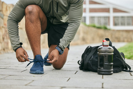 Fitness, sports shoes and black man tie before outdoor cardio exercise or workout in the park....