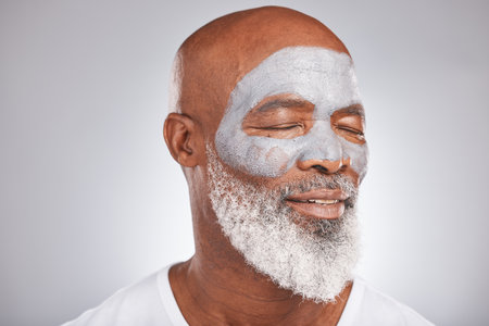 Skincare, beauty or senior black man with face mask marketing or advertising a luxury beauty product for self care. Studio background, facial cosmetics or African old man relaxing with a happy smileの写真素材