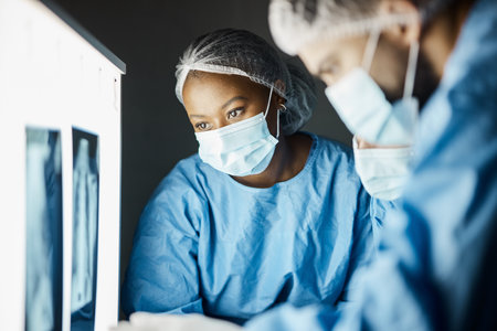 X ray, exam and covid doctors meeting for a healthcare diagnosis, medical inspection and research results. Strategy, teamwork and surgeon workers doing analysis of a body scan with face maskの写真素材