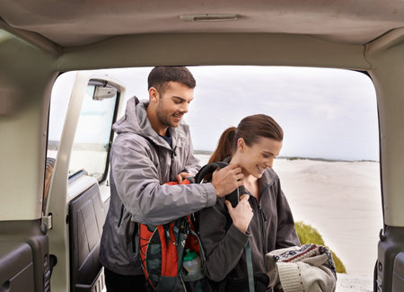 Ready for a hike. a young couple at the back of their car while on a roadtrip.