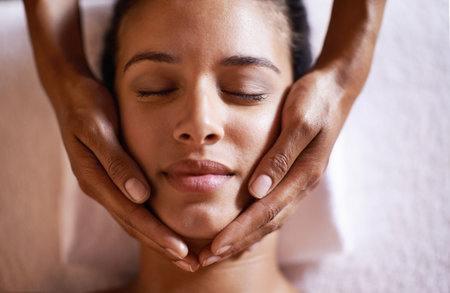 That feels divine. a young woman getting a head massage at a beauty spa.の写真素材