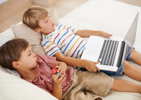 Keeping themselves busy. Two boys watching stories on a laptop.の写真素材