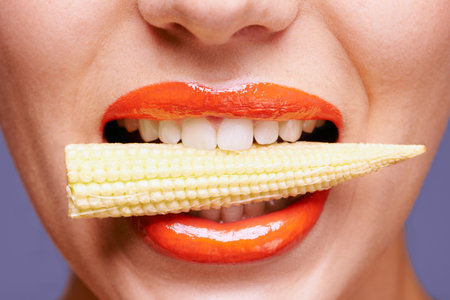 Craving for corn. a beautiful young woman eating baby corn.