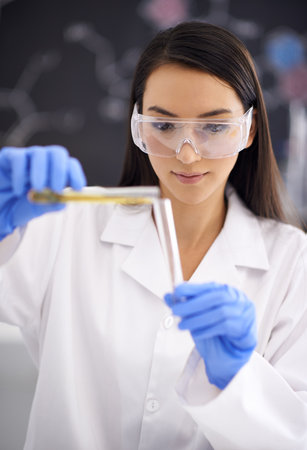 Dont spill a drop. a female scientist pouring liquid into a test tube.の写真素材