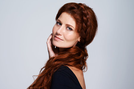 Going for that soft style. Studio shot of a young woman with beautiful red hair posing against a...