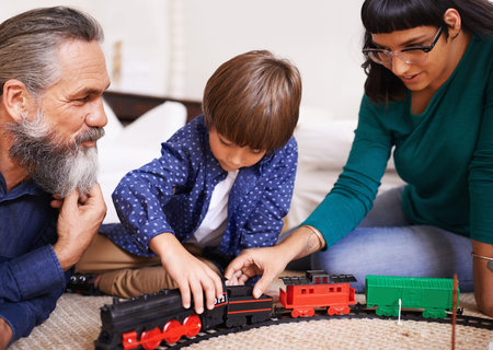 Showing the grownups how to assemble the train. a mother and grandfather watching a child play with...