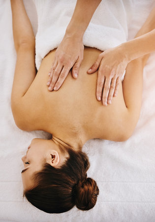 Her hands know just where to touch. a beautiful young woman enjoying a back massage at a spa.の写真素材