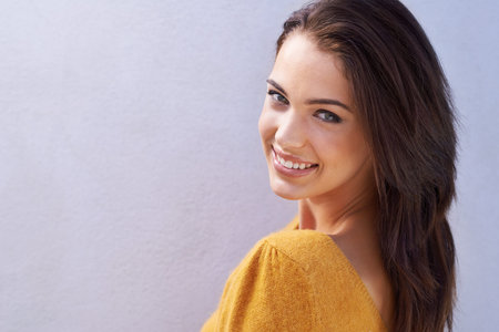 Her smile is beautiful. Portrait of a beautiful young woman looking over her shoulder.
