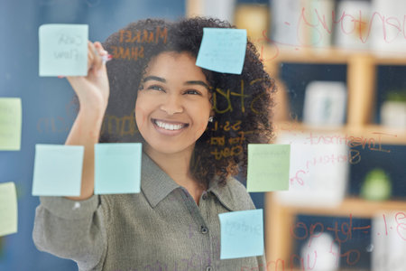 Glass, sticky notes and woman writing idea, planning and strategy in office, happy and vision. Wall,...