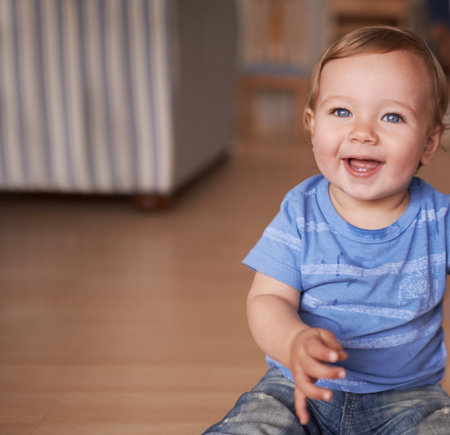 The cutest smile. an adorable little infant sitting on the floor.