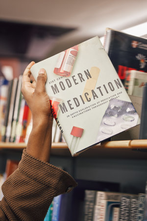 Book in hand, library and student of medicine, pills and healthcare education and learning about pharmaceutical drugs. Black woman with reading information, learn and study, research for medical testの写真素材