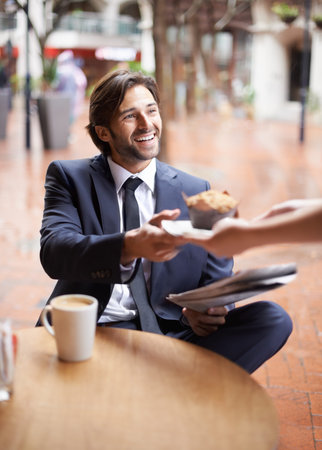 Thank you very much. A happy businessman being served a muffin at a coffee shop.の写真素材