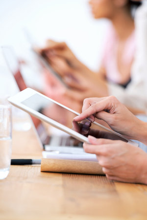 Wireless freedom in the boardroom. a group of businesspeople using their wireless devices during a...
