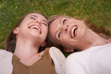 Carefree moments together. A mother and daughter lying with their heads together on the grass.の写真素材