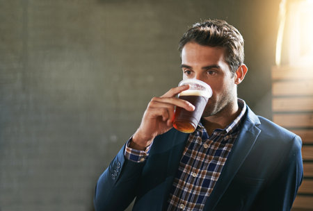 Theres nothing better than a beer after a long day. a man enjoying an ice cold beer at his local bar.の写真素材